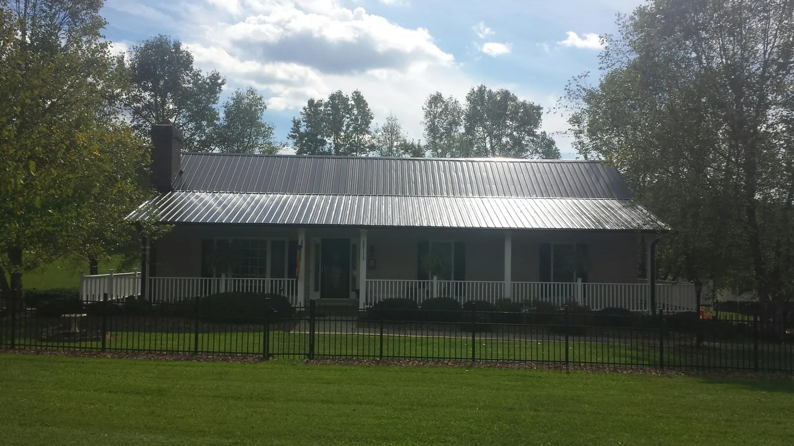 Gray metal roof on a brick ranch with a full width front porch — Gutter Guard Installation work by our crew in Dorchester
