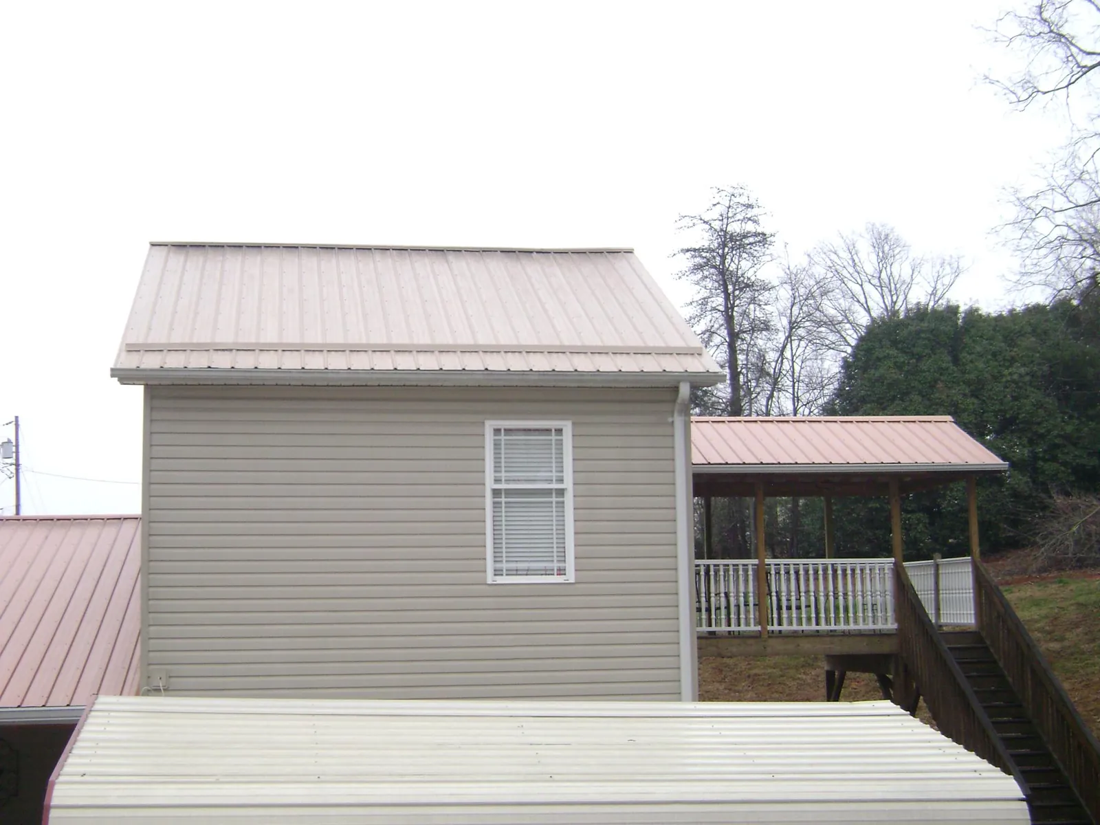 Tan metal roofs on a two story addition and attached porch, from a Roof Replacement job in Dorchester